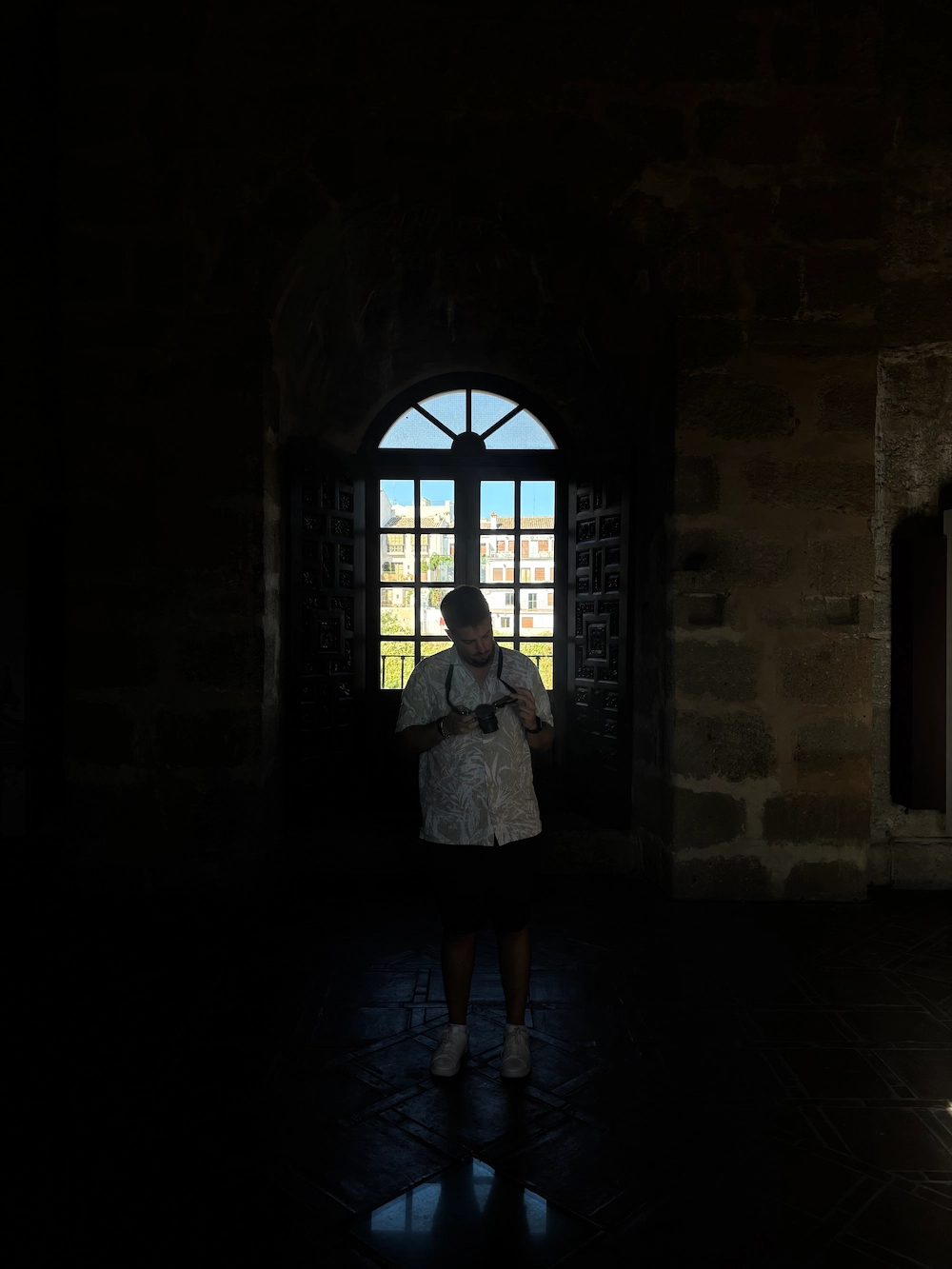Diogo Carvalheiro a fotografar em contraluz, junto a uma janela de um edifício histórico